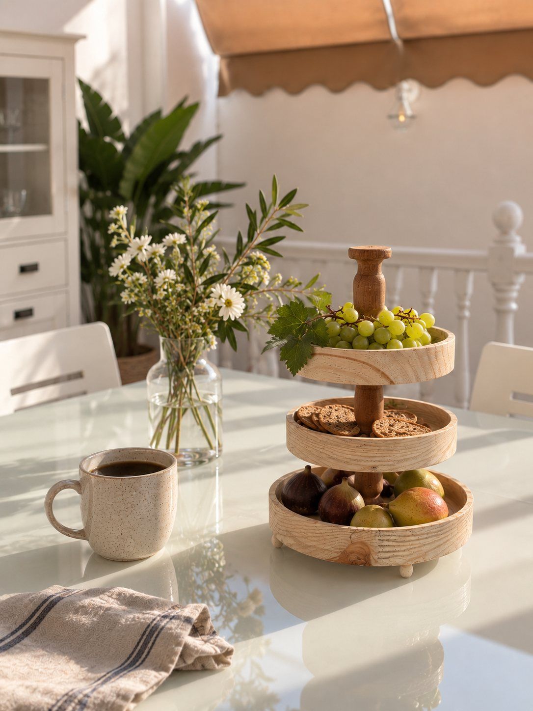 A tiered stand of fruit, coffee and fresh flowers on the terrace table.