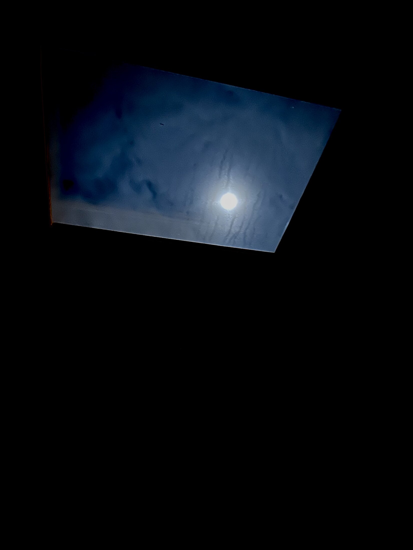 The moon seen through a skylight above the bed at dawn.